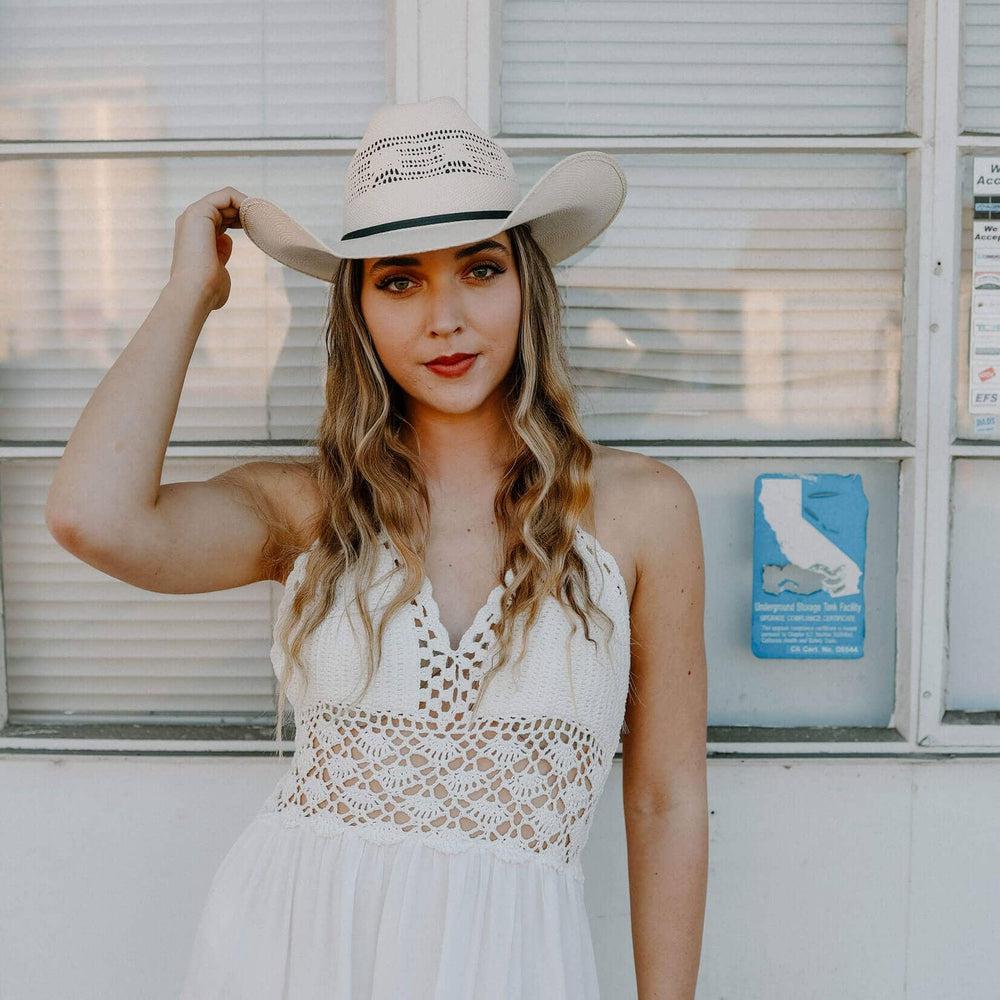 A woman in white dress wearing Bozeman Cream Straw Cowboy Hat