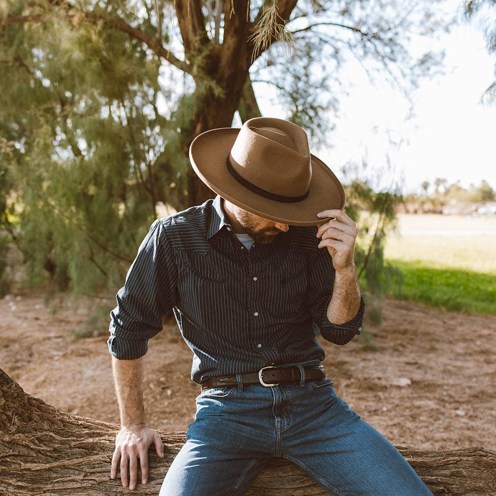 A man sitting on a tree wearing Hudson Bark Felt Fedora Hat