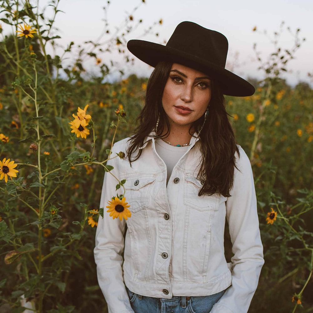 A woman standing around the plants wearing Hudson Black Felt Fedora Hat