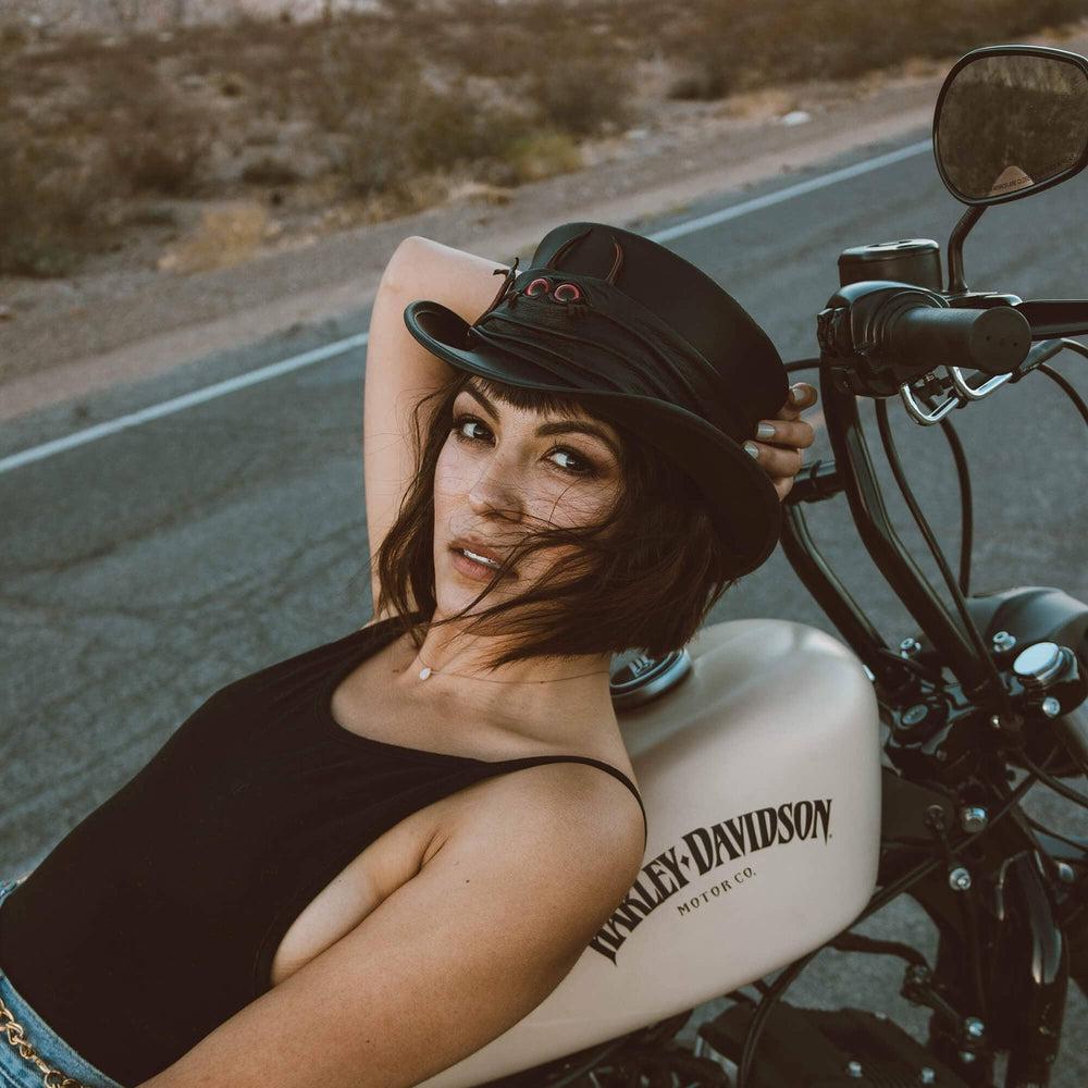 A woman on a motorcycle wearing Lil Evil Black Leather Top Hat