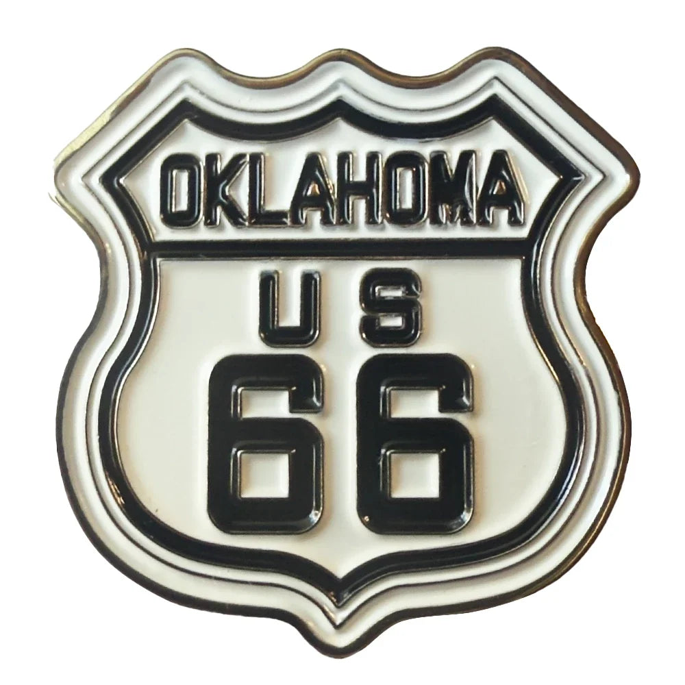 An enamel shield-shaped pin featuring the 'Oklahoma US 66' Route 66 design, with black lettering and border on a white enamel background.