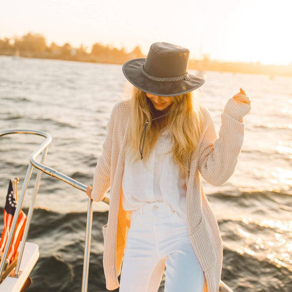 A woman enjoying her boat ride wearing knitted jacket and a hat