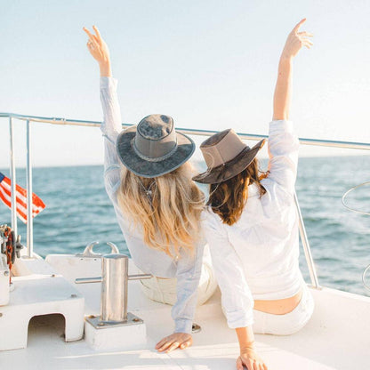 Two woman sitting on a boat wearing polo shirts and hats