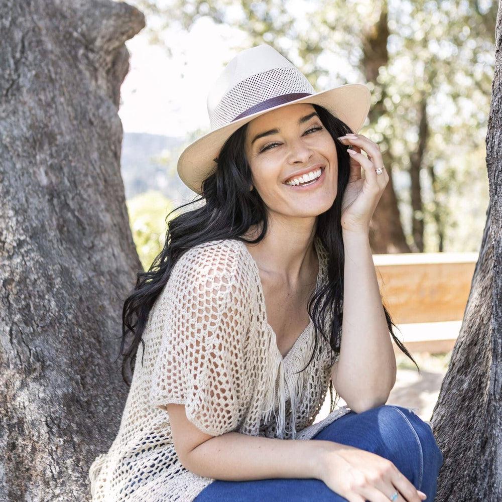 A woman sitting under the tree with a knitted blouse and Cream Straw Fedora Hat 