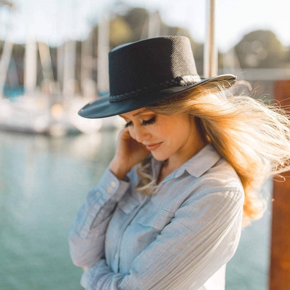 A woman on a boat facing side view wearing a black hat