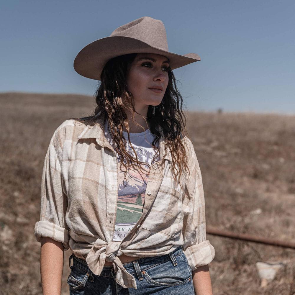 A woman in a checkered top and a Felt Cowboy Hat 