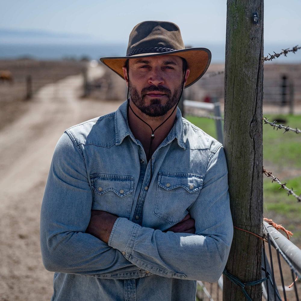 A man standing outdoor wearing Brown Outback Leather Hat 