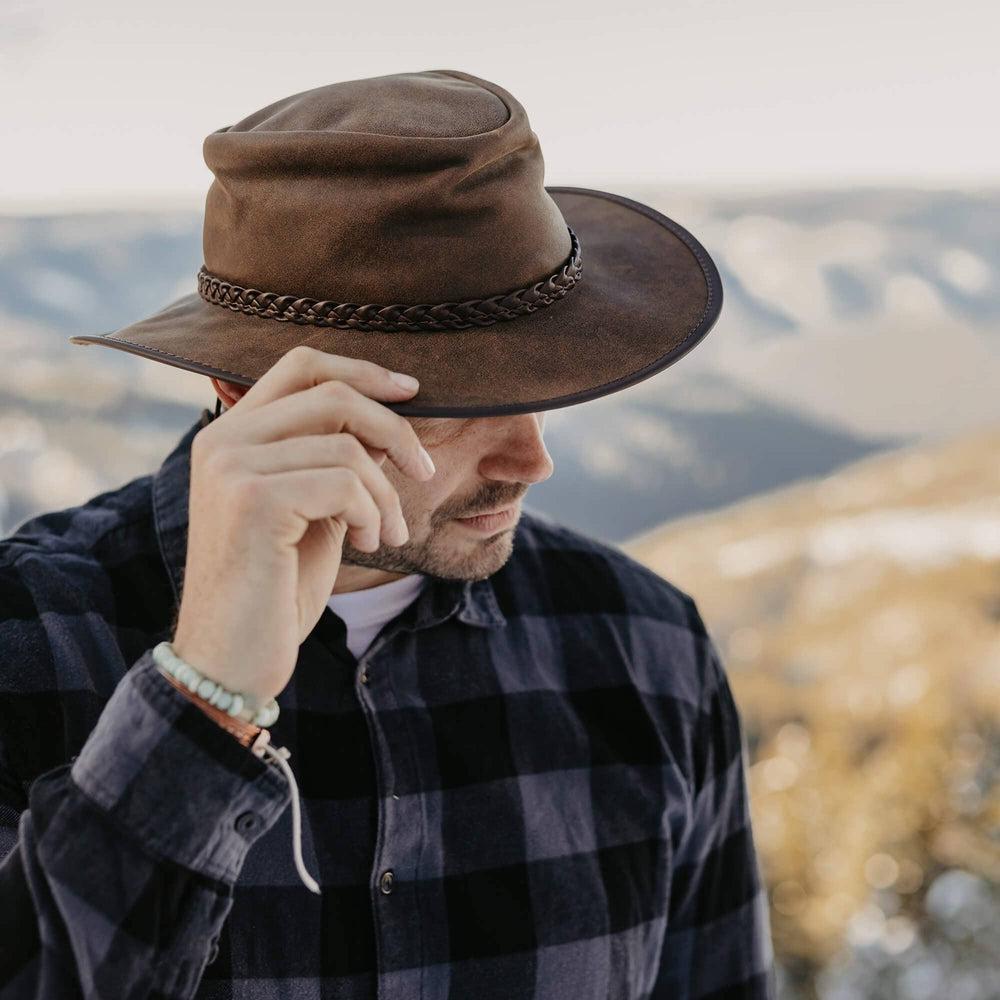 A man on a checkered polo wearing Crusher Bomber Brown Outback Leather Hat 