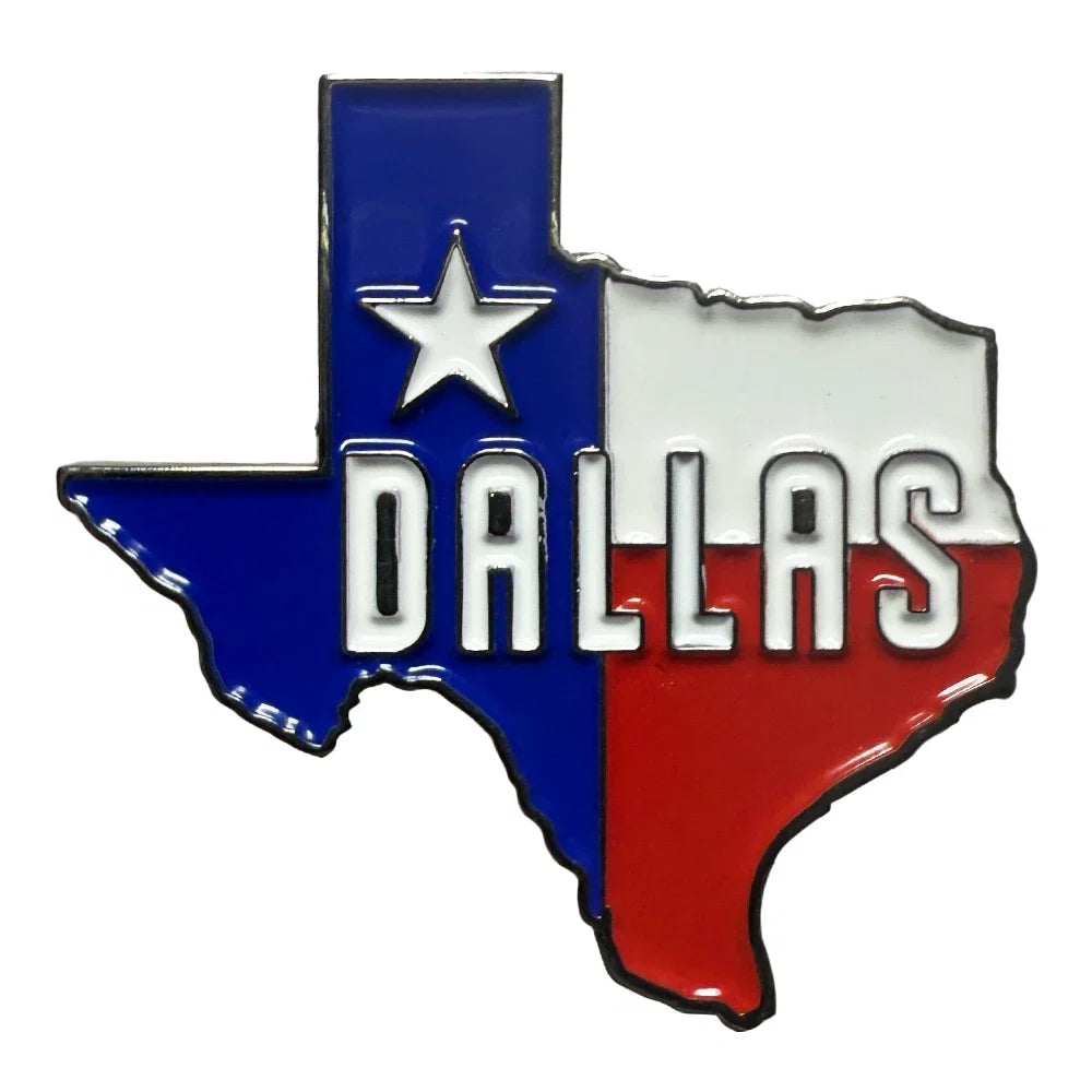 A Texas-shaped enamel pin featuring the Dallas skyline silhouette, filled with the Texas flag colors: blue vertical section with a white star and the word 'DALLAS' in white, white horizontal section, and red lower section, outlined in black on a white background.