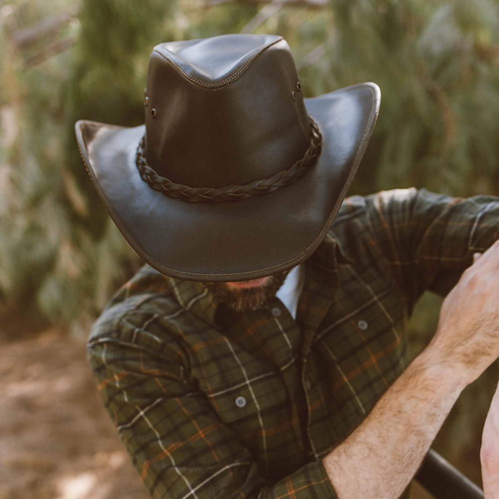 A man wearing checkered polo and a Brown Leather Cowboy Hat 