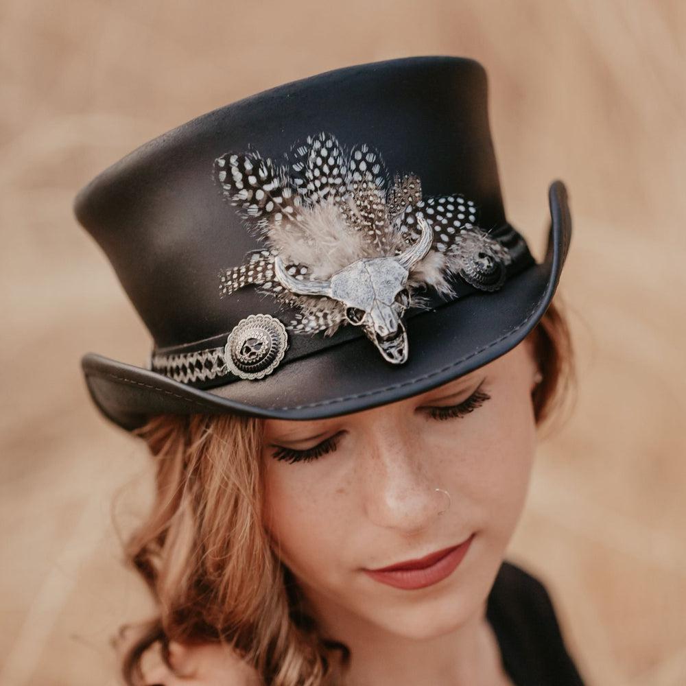 A woman wearing a black top hat with a true grit hat band