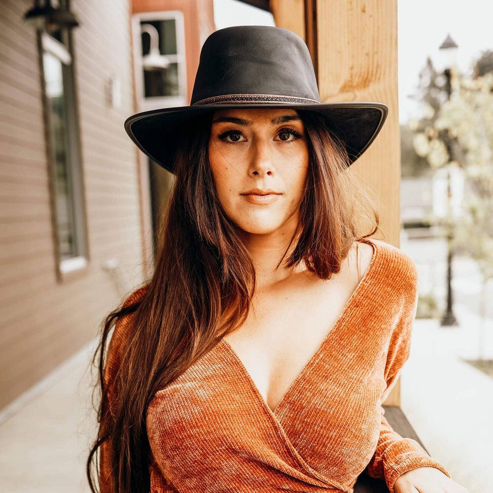 A woman wearing brown blouse and a Midnight Black Rider Leather Hat 