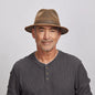 Portrait of a smiling middle-aged man wearing a brown Otis leather hat and a gray henley shirt