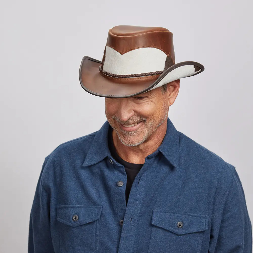 Middle-aged man smiling, wearing a brown Pinto leather hat and a dark blue button-up.