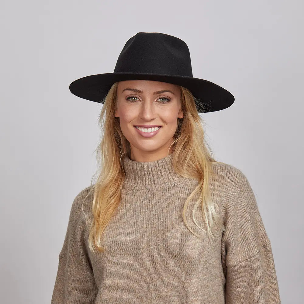 Woman with long blonde hair wearing a beige turtleneck sweater and a black Rancher hat.