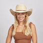 A smiling young woman with blonde hair wearing a Roper Cowboy Hat and a brown sleeveless top. 