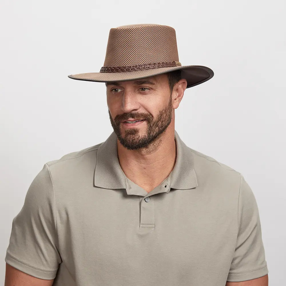 Man wearing a brown mesh fedora and a light beige polo shirt.