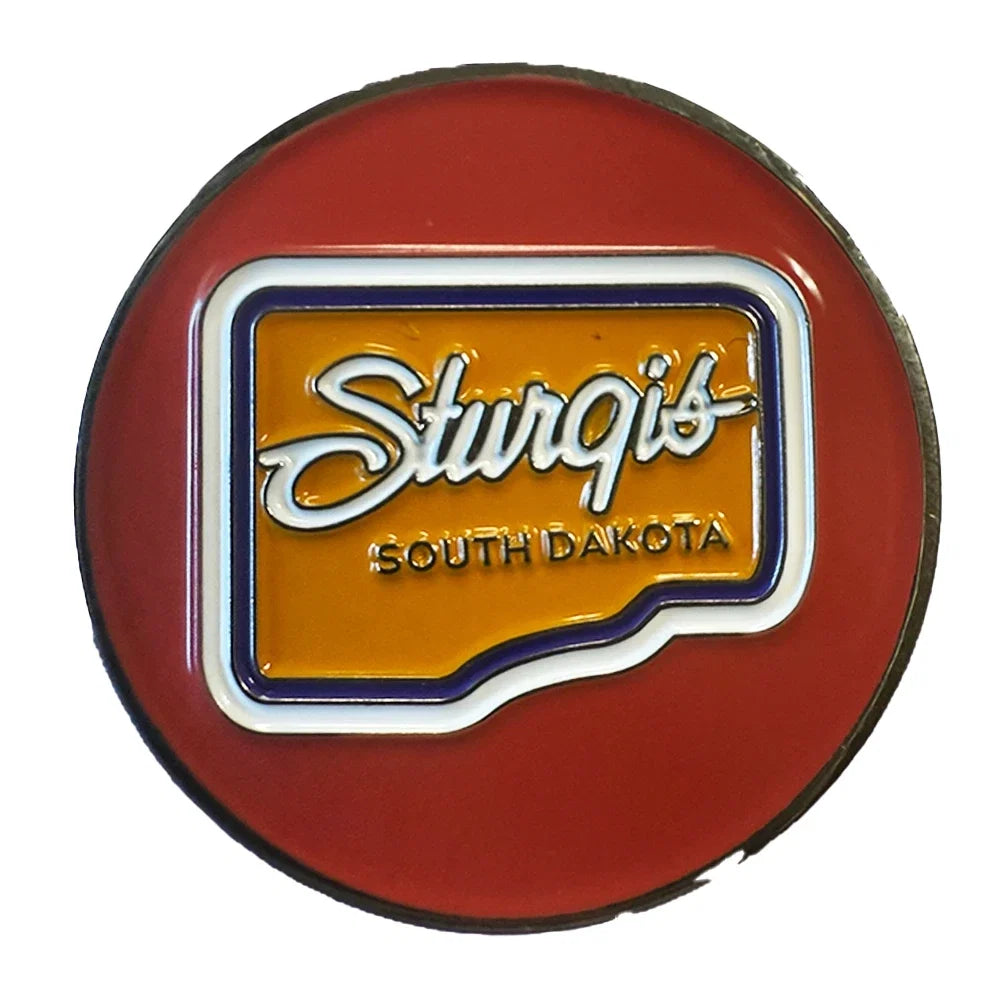A circular red Sturgis South Dakota novelty pin or badge featuring a yellow-orange center with white script lettering and blue border details, shown on a plain white background.