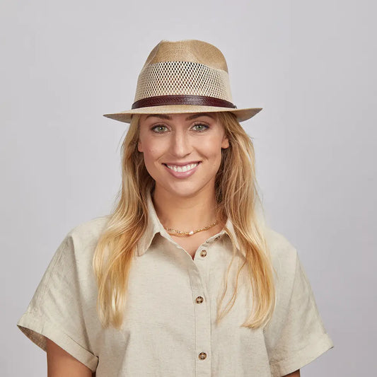 A happy woman wearing a cream top and the cream Tuscany straw sun hat