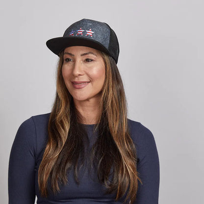 A long haired woman wearing a navy blue top and a mesh poly cap