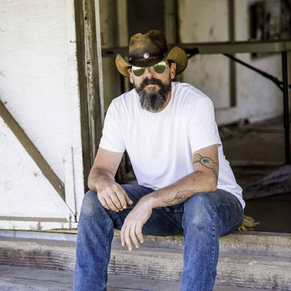 A man sitting down wearing a white shirt and a Cobblestone Leather Cowboy Hat with 3" Brim and 4" Crown 