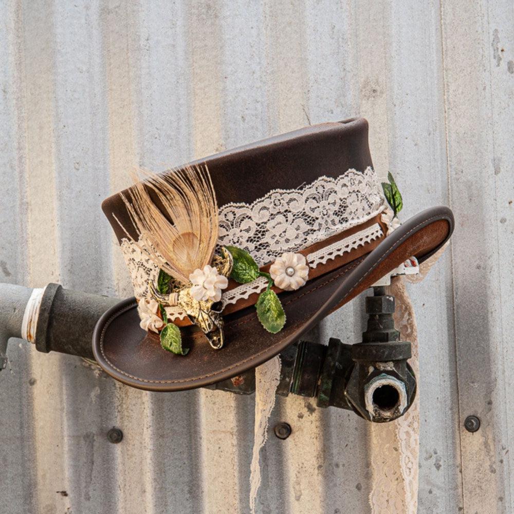 A brown leather top hat beaded with true love hat band placed on a faucet tubing