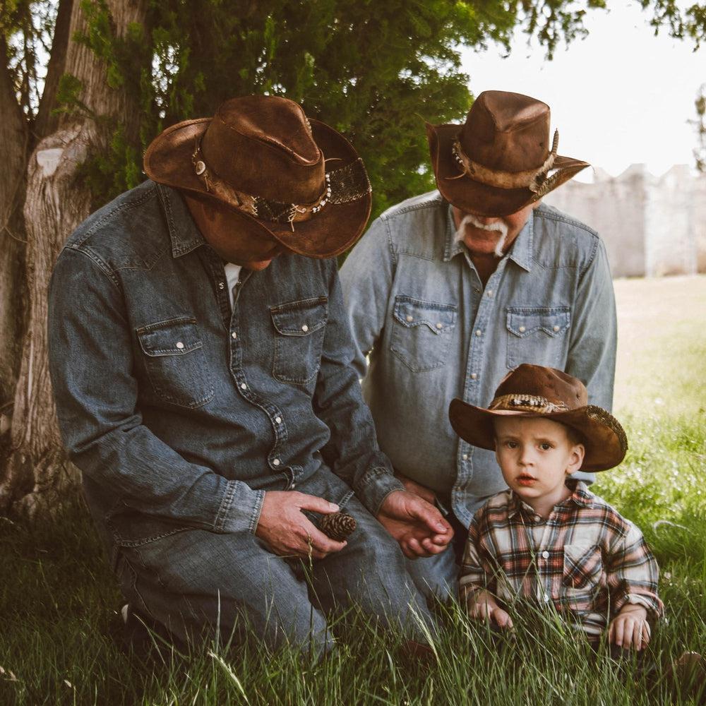 A family talking under a tree wearing brown hats